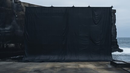 a huge black tarpaulin in between two massive black concrete wall sea defense on the ocean - obrazy, fototapety, plakaty