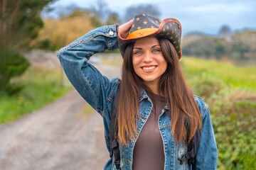 Smiling radiant woman with cowboy hat on a rural path