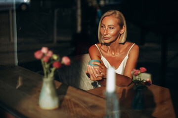 Blonde mature woman drinking coffee in a cafe