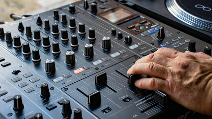 A DJ moving a fader on a mixing console