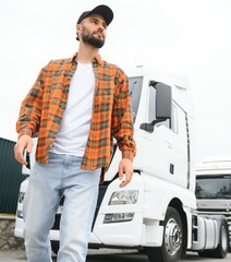 Portrait of young bearded trucker standing by his truck vehicle. Transportation service. Truck...