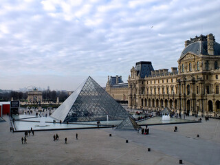 Tourists with the landmark pyramid outside the Louvre museum in Paris, France - Powered by Adobe