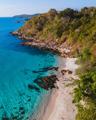 Koh Samet Island Thailand, aerial drone view from above at a couple of men and woman on the beach of Samed Island in Thailand with a turqouse colored ocean and a white tropical beach