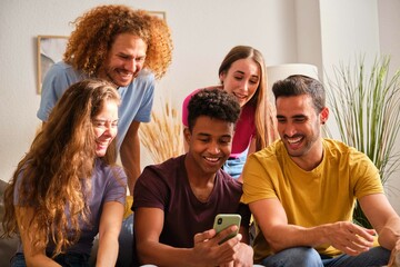 Group of cheerful young multiethnic friends watching social network funny content on a smartphone screen.