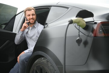 A man charges his modern electric car. The concept of green energy