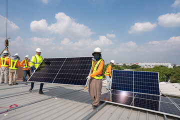 Men technicians carrying photovoltaic solar moduls on roof of factory on the morning. Installing a...