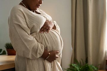 African American pregnant woman stroking her belly and waiting for her daughter