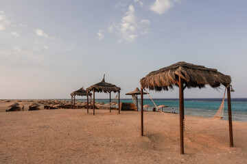 Fototapeta na wymiar three cozy hammocks with a reed roof at the sandy beach at the red sea