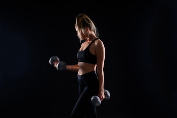 Muscular woman doing exercises with dumbbells at biceps. Photo of strong female isolated on studio