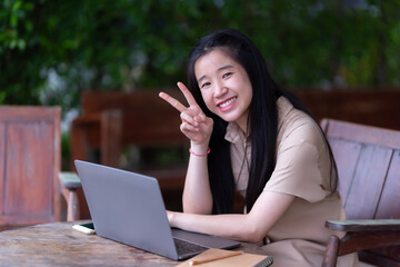 Happy of Young asian teen girl college student using laptop computer writing on pc working from at the cafe.Online education, elearning concept,freelance people businessfemale