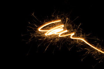 Burning gold sparkler line as swirl, spiral or funnel on black background. Christmas festive...