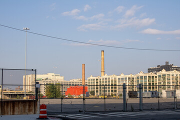 Cityscape with tall industrial buildings in the background, behind a metal fence