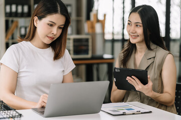 Business, technology and office concept - two businessmen with laptop, tablet pc computer and papers having discussion in modern office.
