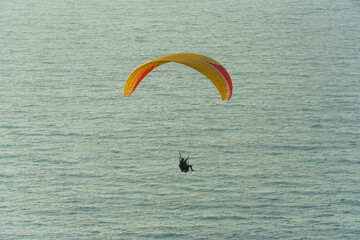 Paragliding in the sky over the sea. The concept of parachute flight. Tandem skydiver pilot and...