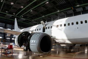 White passenger airliner in the aviation hangar. Aircraft under maintenance. Checking mechanical...
