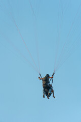 Paragliding in the sky over the sea. The concept of parachute flight. Tandem skydiver pilot and passenger fly on a sunny day.