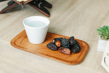 A cup of mineral water and dates fruit on wooden tray. Healthy food concept