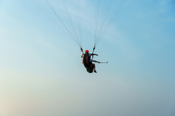 Paragliding in the sky over the sea. The concept of parachute flight. Tandem skydiver pilot and passenger fly on a sunny day.