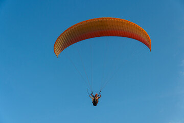 Paragliding in the sky over the sea. The concept of parachute flight. Tandem skydiver pilot and passenger fly on a sunny day.
