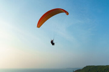 Paragliding in the sky over the sea. The concept of parachute flight. Tandem skydiver pilot and passenger fly on a sunny day.