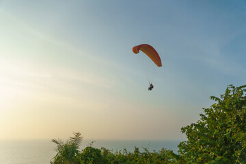 Paragliding in the sky over the sea. The concept of parachute flight. Tandem skydiver pilot and...