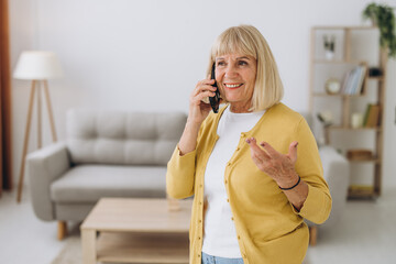 Senior old elderly caucasian woman grandmother talking by smart phone in living room