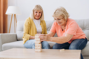 Two senior women female woman friends or family sisters play leisure board game at home