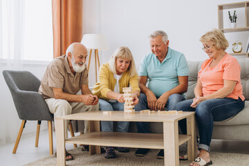 Group of happy senior people having fun and playing board games in retirement home