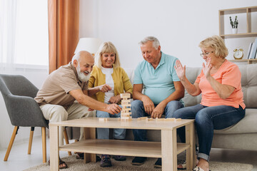 Group of happy senior people having fun and playing board games in retirement home