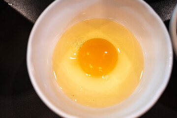 Fresh raw egg in a white bowl. Preparation of omelet