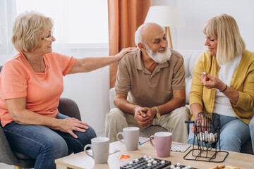 Group of four cheerful senior people playing bingo game in nursing home