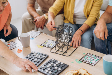 Group of four cheerful senior people playing bingo game in nursing home