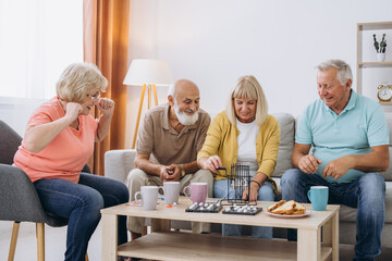 Obraz premium Group of four cheerful senior people playing bingo game in nursing home