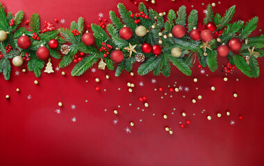 Branches of the Christmas tree and decorative accessories on red background.