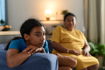 Adult daughter having a conflict with her mother while sitting on sofa in the room - obrazy, fototapety, plakaty