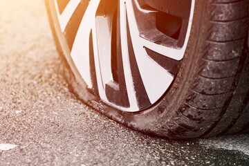 Car wheel flat tire on the road. Punctured vehicle tire. Roadside assistance.