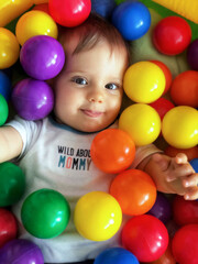 Fototapeta na wymiar My Little One in a Sea of Colorful Balls: Laughter that Echoes Happiness