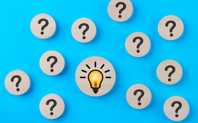 Problem solving concept. Question mark and light bulb icons on round wooden on blue background....