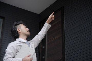 外壁や壁面、定期点検をなどの確認をする作業着の人　指さし確認