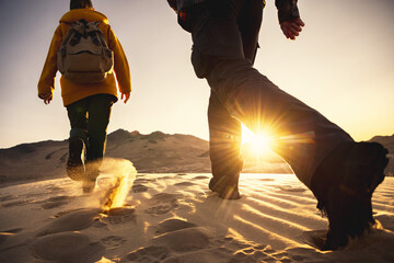 Two hikers with backpacks walks in sunset desert dunes. Close up photo of hiking boots. Hiking...