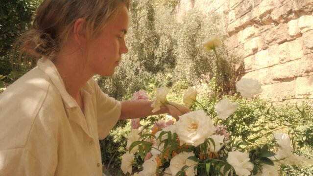 Woman florist create white rose flowers bouquet decor for summer garden party outdoor wedding