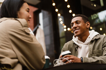 Happy couple drinking coffee while sitting in cafe outdoors