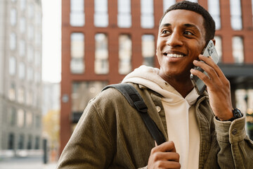 Smiling man talking on cellphone while standing at city street