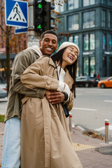 Cheerful couple hugging while standing at city street