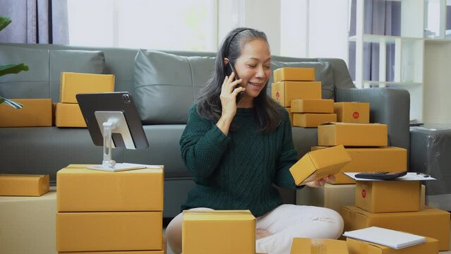 Startup small business entrepreneur or freelance using a laptop with box, checking orders from customers, matron runs an e-commerce business on websites and social media. 