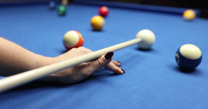 Hand with cue pointing at billiard ball at table. Billiards game