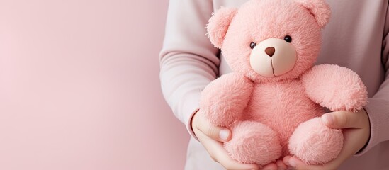 Children hand holds a pink felt Teddy bear. Copy space image. Place for adding text