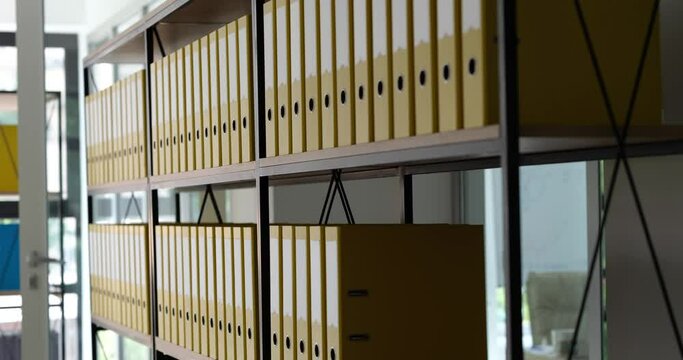 Many yellow identical folders were added to shelf in office. Archive documentation and storage of business documents