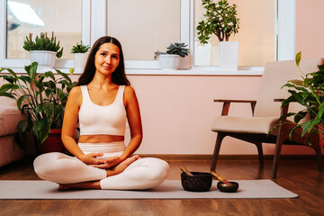 Portrait of beautiful brunette woman yoga teacher sitting in lotus position and lookig to the...