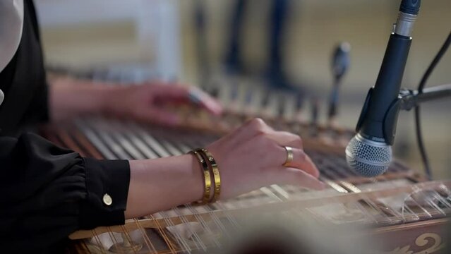 A woman playing on Zither in the theatre static shot, close up shot